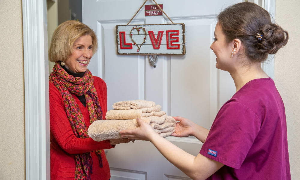A team member delivering fresh linens to a resident at Mountain View Gardens